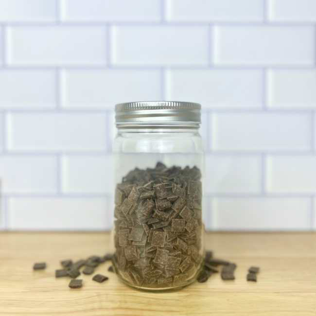 square-shaped dark chocolate chunks in a clear glass mason jar