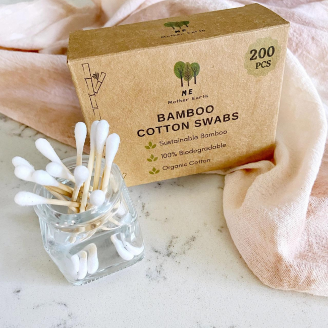 Bamboo cotton swabs in a glass jar next to a paper box of swabs